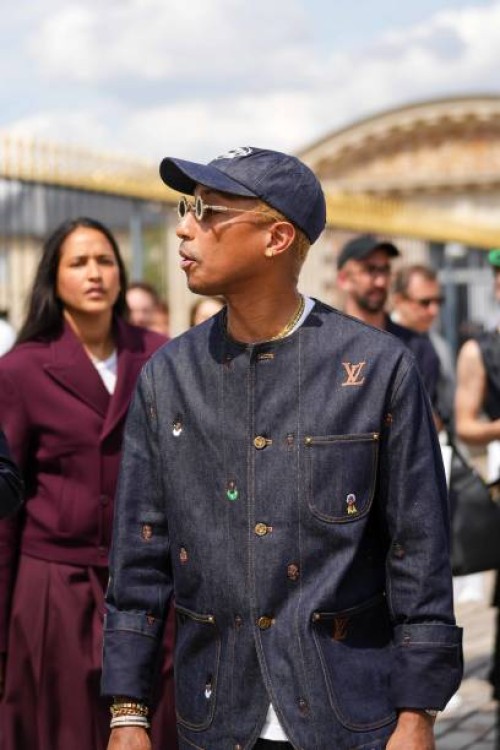 Pharrell Williams wears a navy blue denim with large white embroidered pattern cap, silver and gold rhinestones small circle sunglasses from Louis...