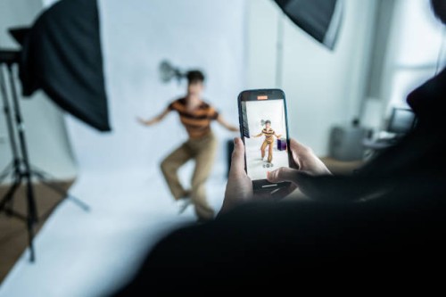 photographer taking photos/filming a young model woman at studio - fashion stock pictures, royalty-free photos & images