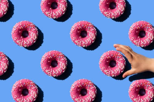 pink doughnut on pastel blue background. child's hand holding a donut. - junk food stock pictures, royalty-free photos & images