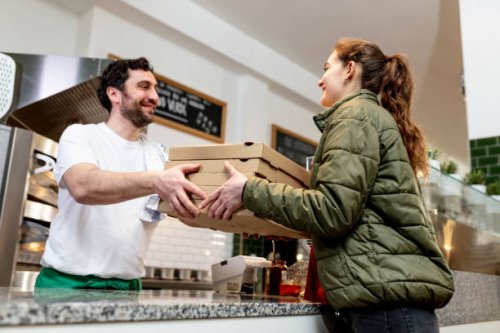 pizzaiolo at work - chef is shovelling fresh prosciutto pizza in the carton pizza box - junk food stock pictures, royalty-free photos & images