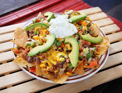 plate of nachos with avocado, cheese and vegetables - junk food stock pictures, royalty-free photos & images