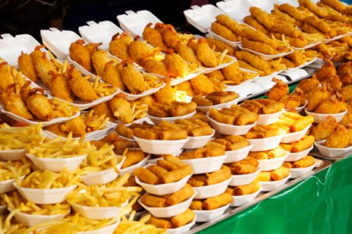 plates of fried food for sale in market - junk food stock pictures, royalty-free photos & images