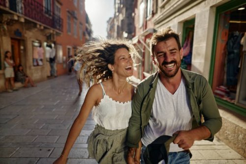 playful couple having fun while running on the street. - travel stock pictures, royalty-free photos & images