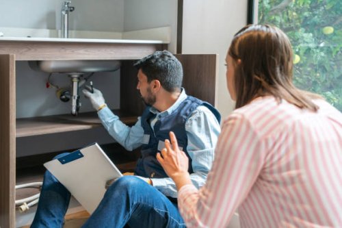 plumber explaining to a client the problem with her kitchen sink - home decoration stock pictures, royalty-free photos & images