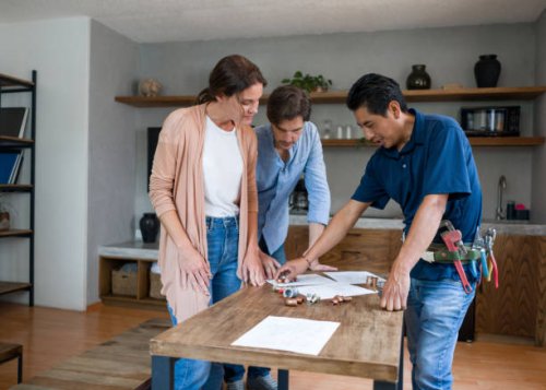 plumber fixing a pipe and talking to his clients in the kitchen - home decoration stock pictures, royalty-free photos & images