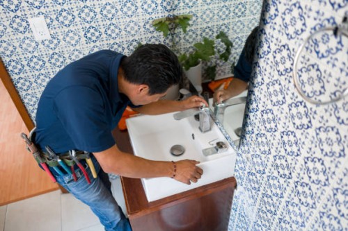 plumber installing a faucet in a bathroom's sink - home decoration stock pictures, royalty-free photos & images