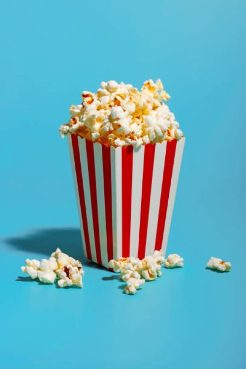 popcorn in red striped container over blue background - junk food stock pictures, royalty-free photos & images