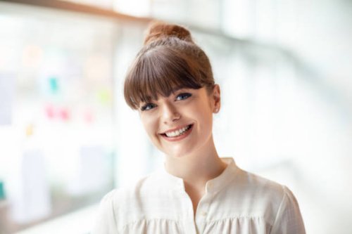 porträt einer jungen frau, die im modernen büro neben dem fenster steht - hairstyle stock-fotos und bilder