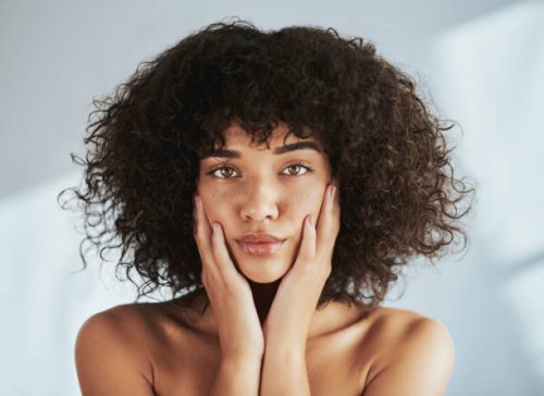 porträt, schönheit und gesicht mit einer schwarzen frau im studio, um natürliche hautpflege oder behandlung zu fördern. gesicht, haut und wellness mit einer attraktiven jungen frau, die ihre wangen berührt für die dermatologi