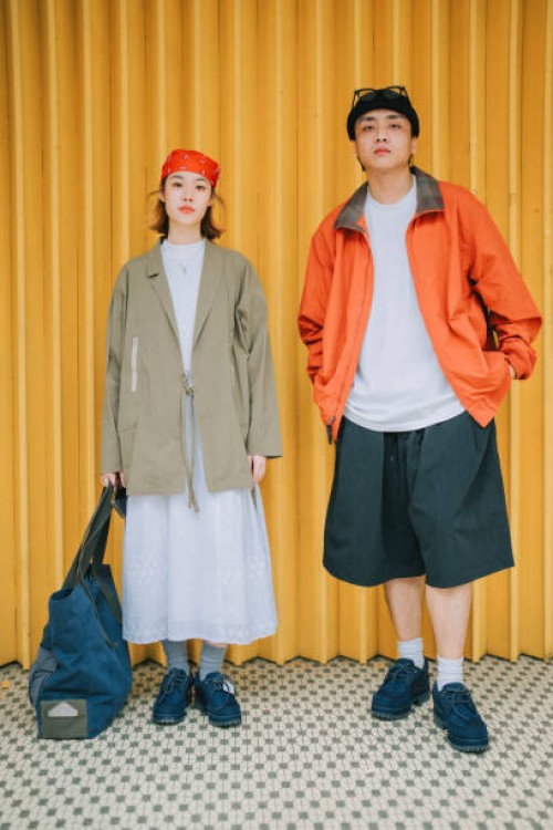 portrait asian chinese young couple with fashionable clothing standing in front of yellow metal gate - fashion stock pictures, royalty-free photos & images