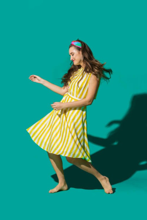 portrait carefree young woman in striped dress dancing against turquoise background - fashion stock pictures, royalty-free photos & images