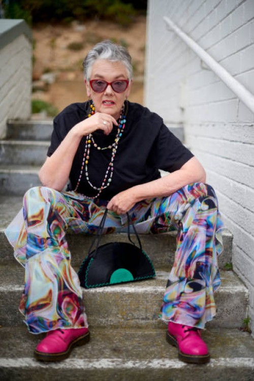 portrait, cool and funky mature woman with stylish and trendy fashion sitting on stairs outdoors. old, elderly and urban outfit by pensioner female with modern and colorful clothes on steps - fashion stock pictures, royalty-f