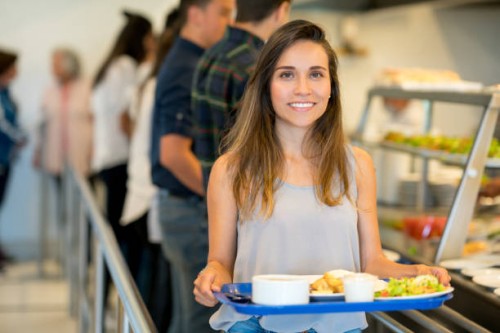 portrait de la belle jeune femme dans un restaurant buffet, tenant son plateau et regardant sourire caméra - food photos et images de collection