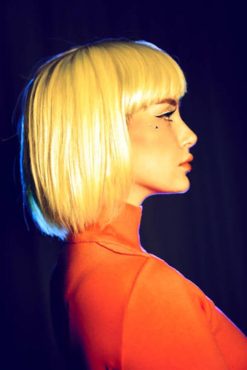 portrait in profile of young woman with yellow hair. yellow and blue lighting, red turtleneck on woman, mock-up for your design with copy space. - fashion stock pictures, royalty-free photos & images