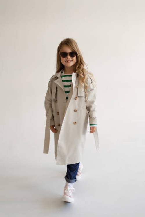portrait of a beautiful fashionable girl with long blonde hair wearing sunglasses jeans and trench coats on a white background in the studio - fashion stock pictures, royalty-free photos & images