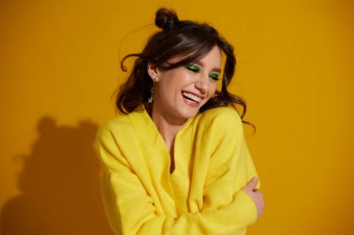 portrait of a beautiful smiling girl with bright makeup and wavy hair on a bright yellow background - fashion photos et images de collection