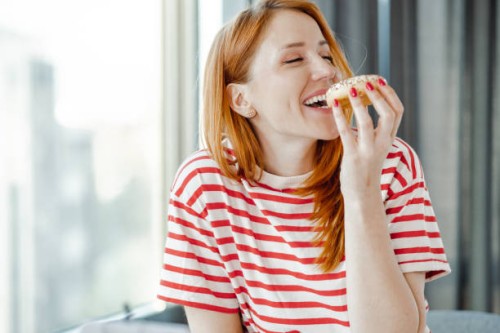 portrait of a beautiful woman enjoying eating a doughnut - food stock pictures, royalty-free photos & images