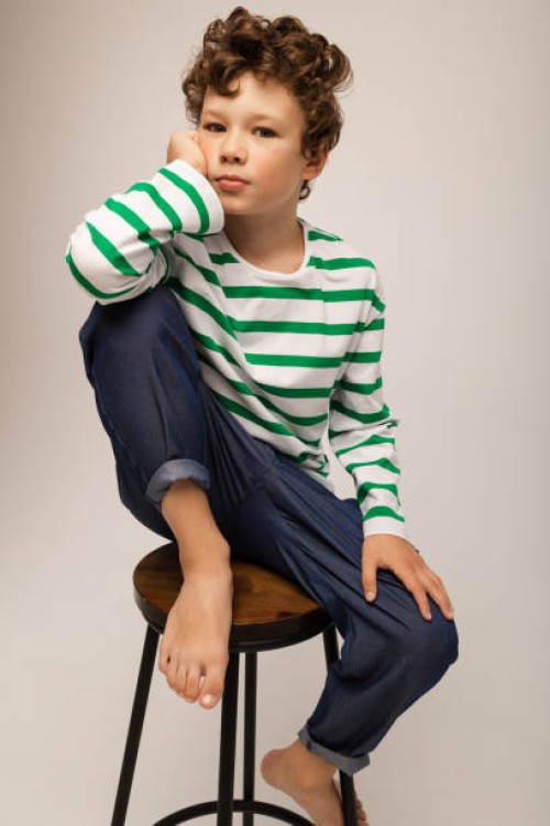 portrait of a curly-haired boy in a vest and jeans on a white background in the studio - fashion photos et images de collection