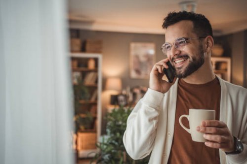 portrait of a handsome caucasian man standing by the window with a cup of coffee in his home - coffee stockfoto's en -beelden