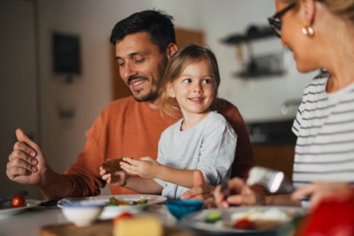portrait of a happy little girl having breakfast with her mother and father at home - food stock pictures, royalty-free photos & images