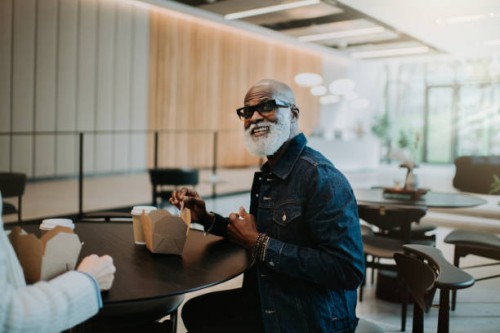 portrait of a happy man enjoying a takeaway lunch in a commercial setting - junk food stock pictures, royalty-free photos & images