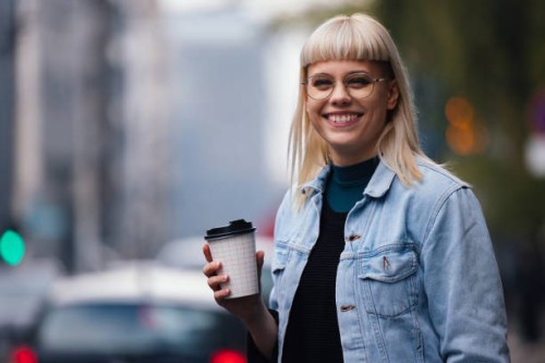 portrait of a happy young woman outdoor holding a paper cup to go - junk food stock pictures, royalty-free photos & images