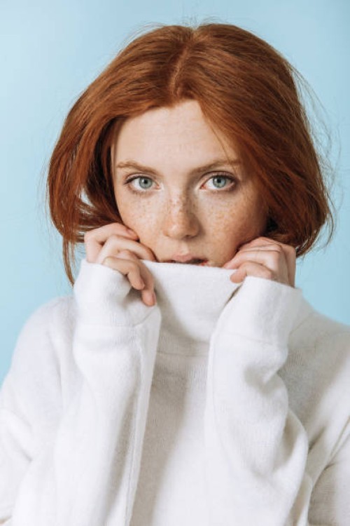 portrait of a red-haired woman in a white sweater with freckles looking into the camera close-up. - fashion stock pictures, royalty-free photos & images
