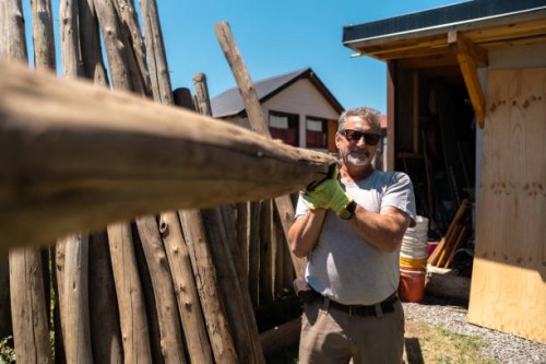portrait of a senior man working holding a tree trunk in a house garden - home decoration stock pictures, royalty-free photos & images