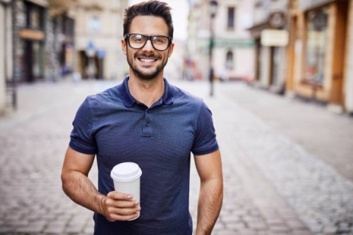portrait of a smiling man with glasses holding coffee outdoors - junk food stock pictures, royalty-free photos & images