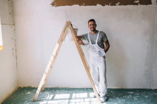portrait of a smiling young man plastering wall in his workshop - home decoration stock pictures, royalty-free photos & images