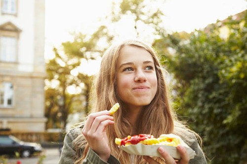 portrait of a teenage girl eating french fries - food stockfoto's en -beelden
