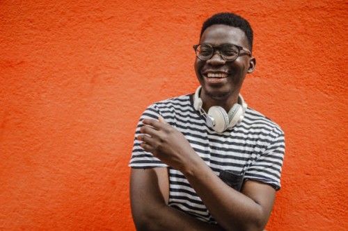 portrait of a young african-american man in front of the orange wall - fashion stock pictures, royalty-free photos & images