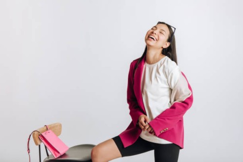 portrait of a young laughing asian woman in a jacket in a studio on a white background - fashion stock pictures, royalty-free photos & images