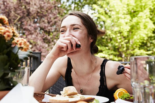 portrait of a young woman fooling around at table eating grapes - food stockfoto's en -beelden