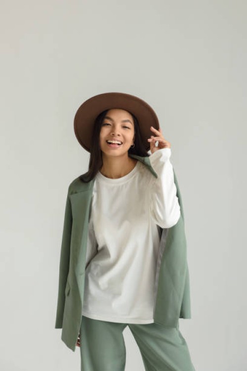 portrait of an asian smiling young woman posing in a hat and beautiful clothes on a white background in the studio. - fashion stock pictures, royalty-free photos & images
