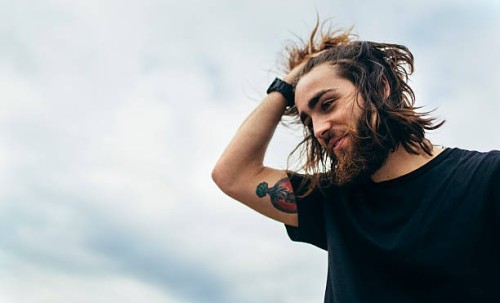 portrait of bearded young man with tattoo on his upper arm - fashion stock pictures, royalty-free photos & images