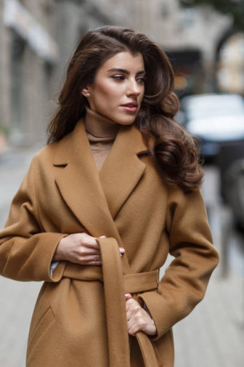 portrait of beautiful lady in light brown coat tying her belt. - fashion stock pictures, royalty-free photos & images