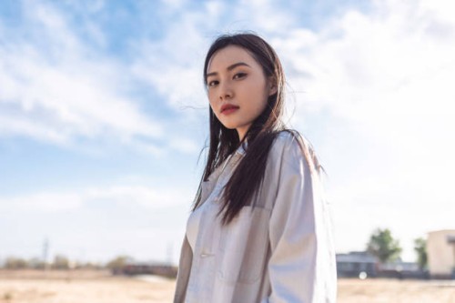 portrait of beautiful young woman, casual clothes and backpack, walking on the dry grass, looking at the camera and smiling - fashion stock pictures, royalty-free photos & images