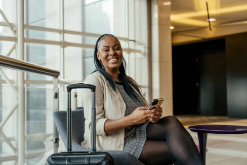 portrait of businesswoman in hotel lobby holding smartphone - travel stockfoto's en -beelden