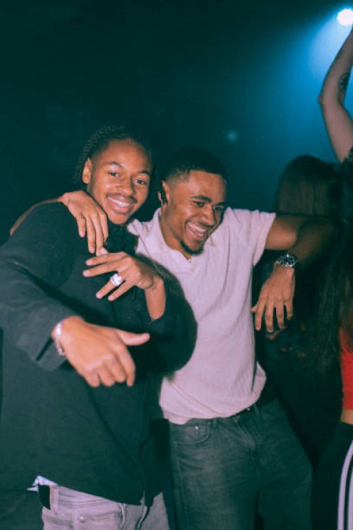 portrait of cheerful young man dancing with male friend at nightclub - concert stock pictures, royalty-free photos & images