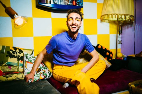 portrait of cheerful young man sitting on sofa in living room - fashion stock pictures, royalty-free photos & images