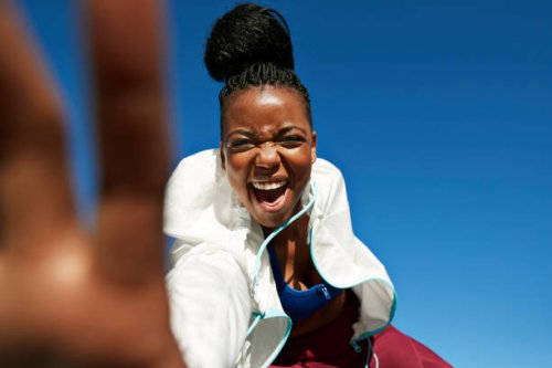 portrait of cheerful young sportswoman with hair bun against clear blue sky - hairstyle stock pictures, royalty-free photos & images