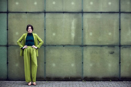 portrait of confident businesswoman wearing green suit standing at a wall - fashion stock pictures, royalty-free photos & images