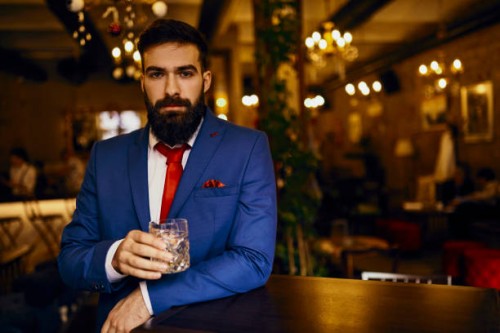 portrait of elegant young man in a bar holding tumbler - fashion stock pictures, royalty-free photos & images