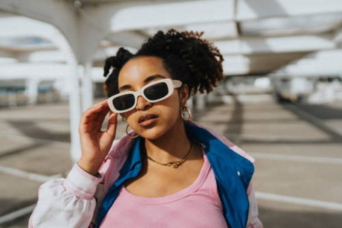 portrait of fashionable curly hair woman holding sunglasses at parking lot in sunlight - fashion stock pictures, royalty-free photos & images