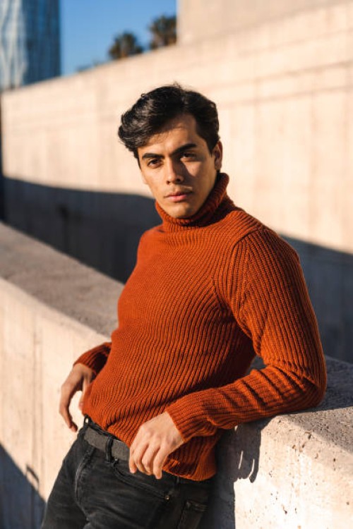 portrait of fashionable young man wearing turtleneck pullover leaning on a wall at sunlight - fashion stock pictures, royalty-free photos & images