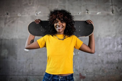 portrait of female skateboarder in warehouse environment - fashion stock pictures, royalty-free photos & images