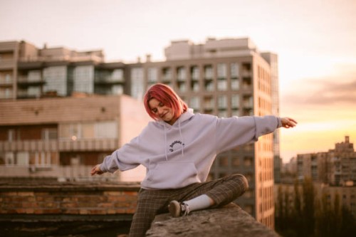 portrait of happy young woman sitting on the roof at sunset - fashion stock pictures, royalty-free photos & images