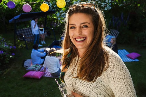 portrait of happy young woman with friends in background at yard during summer party - garden decoration stock pictures, royalty-free photos & images