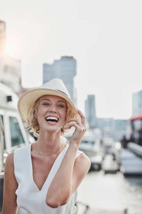 portrait of laughing young woman wearing a hat at a marina - fashion stock pictures, royalty-free photos & images